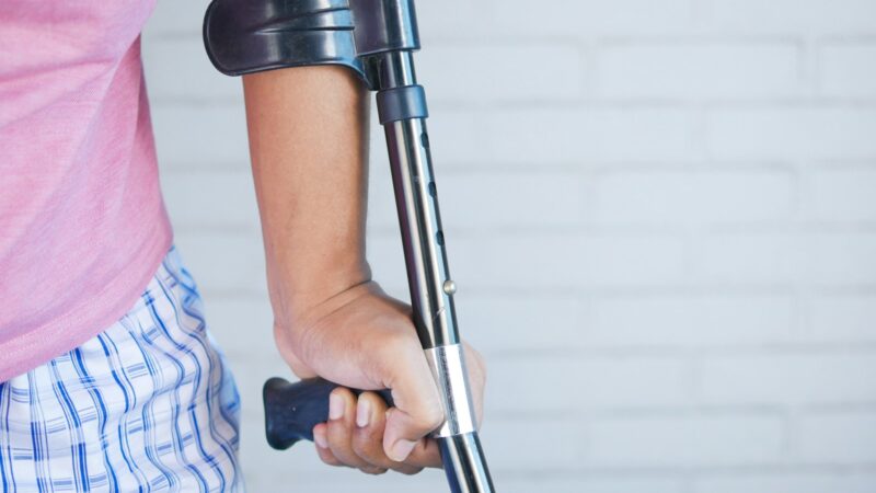 a person holding a crutch and walking cane