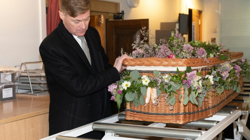 a man in a suit and tie holding a basket of flowers